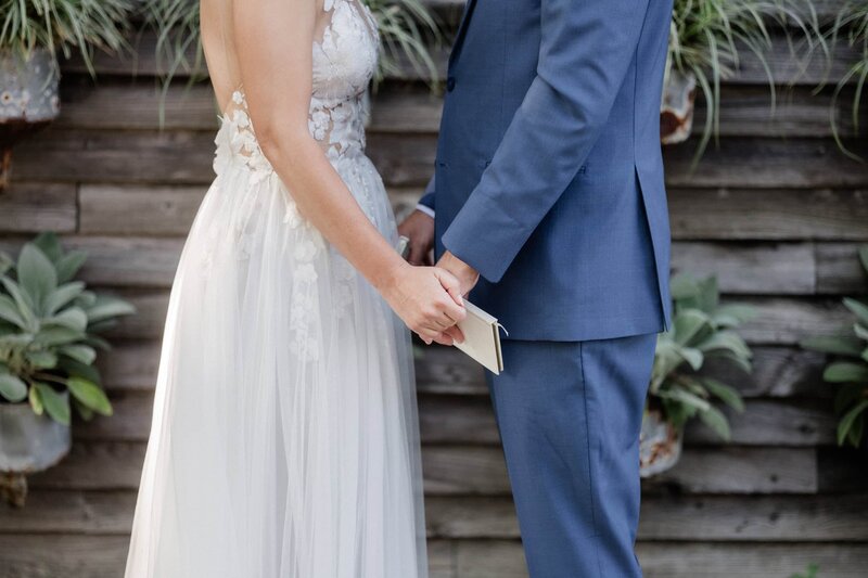 Close up of the hands of the two brides reading their private vows at the Peter Shields Inn suite