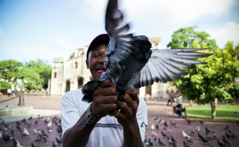 A man catches a bird in front of an old church in the Dominican Republic.