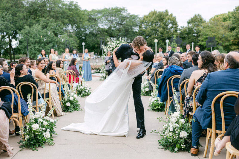 groom dips bride in wedding aisle
