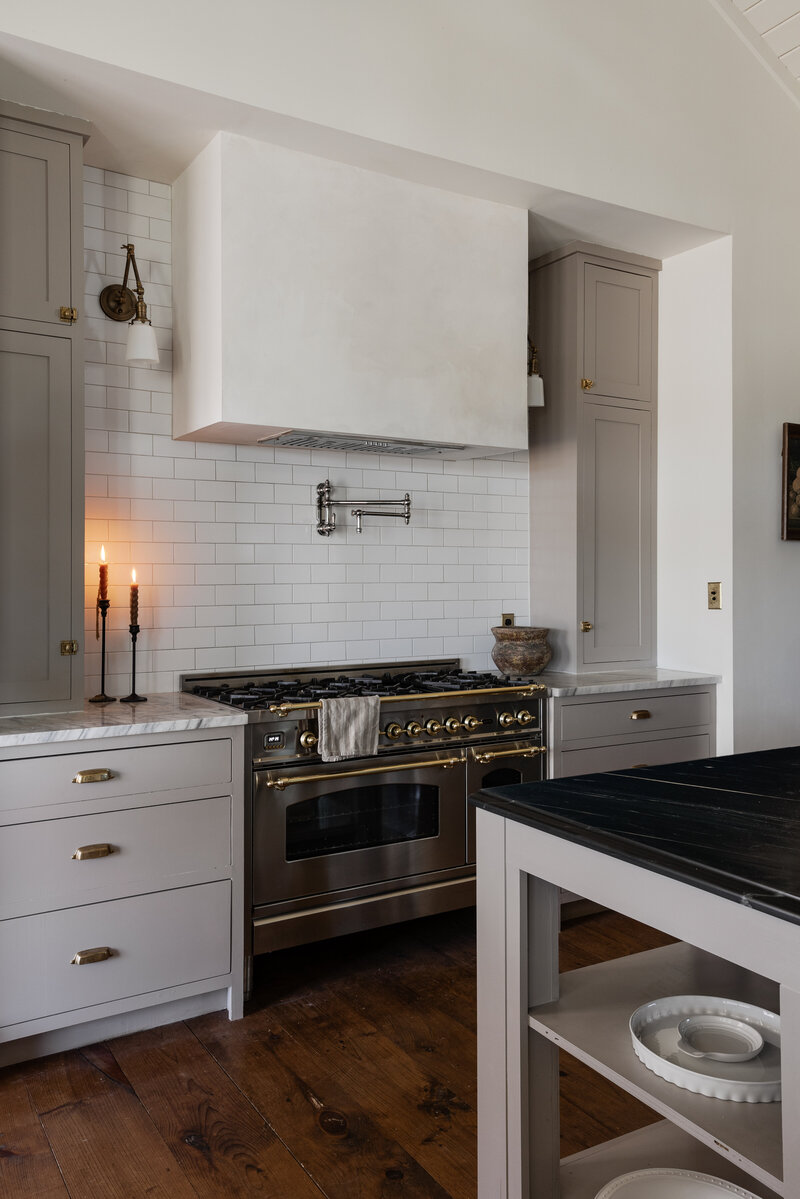 A European range, lime washed hood, classic subway tile, Carrara Marble on the countertops and Bluestone on the island make this kitchen extra special. By Jessa Myer Interiors.