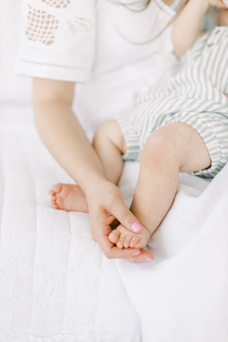 Mom gently holds her sons foot during his first birthday session.