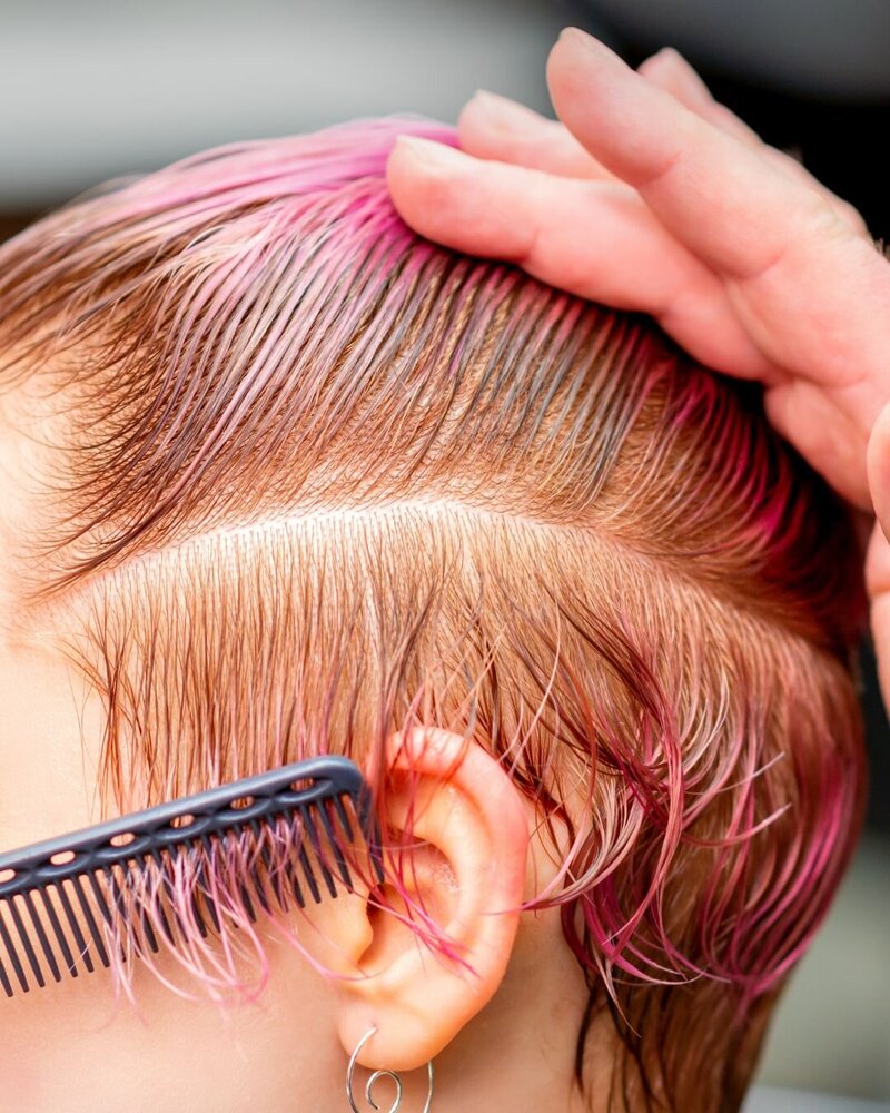 Woman with thinning, fine hair sits in a chair while the hairstylist combs through solutions