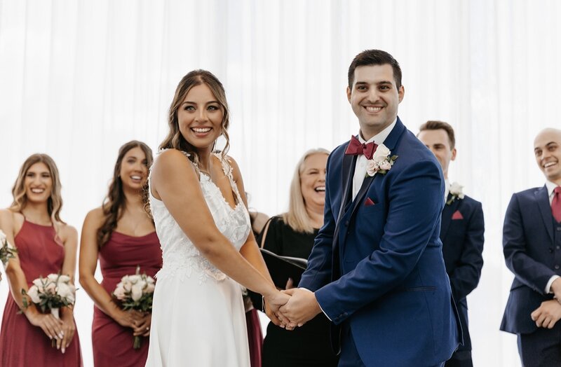 Bride and groom holding hands smiling at camera