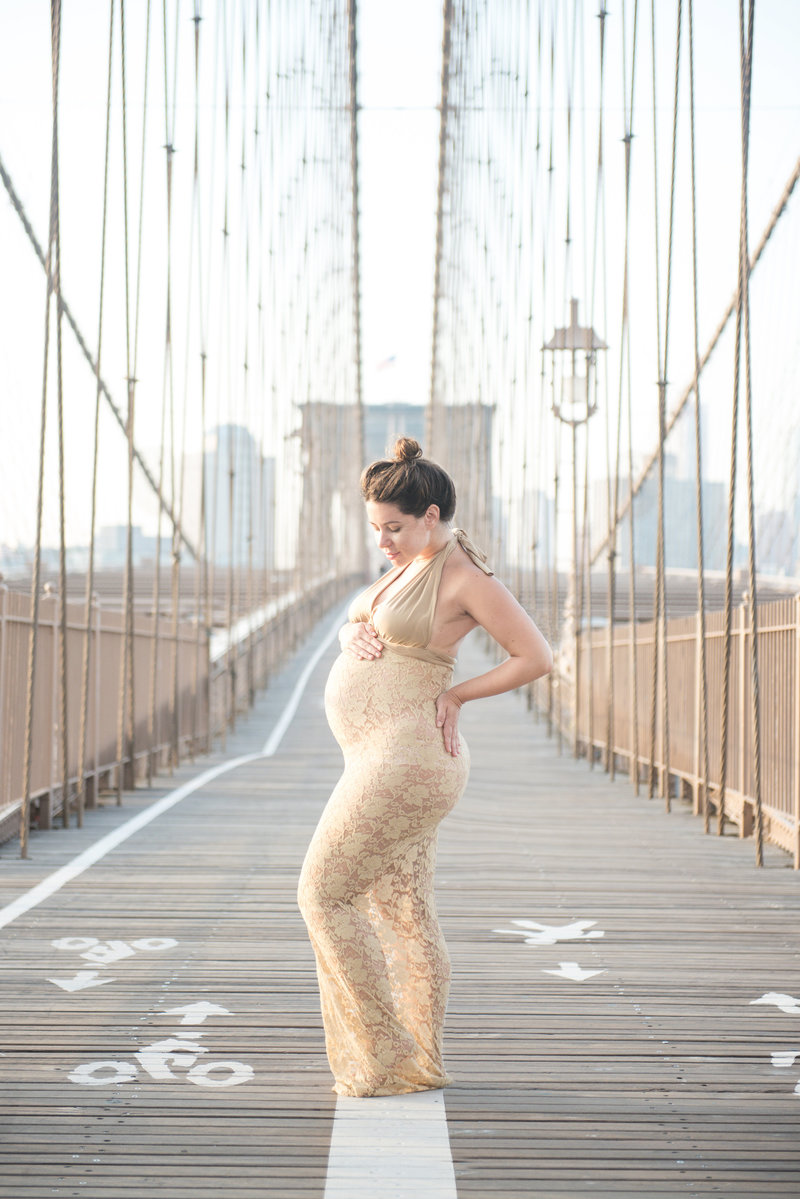 pregnant mom in gold lace dress on the brooklyn bridge