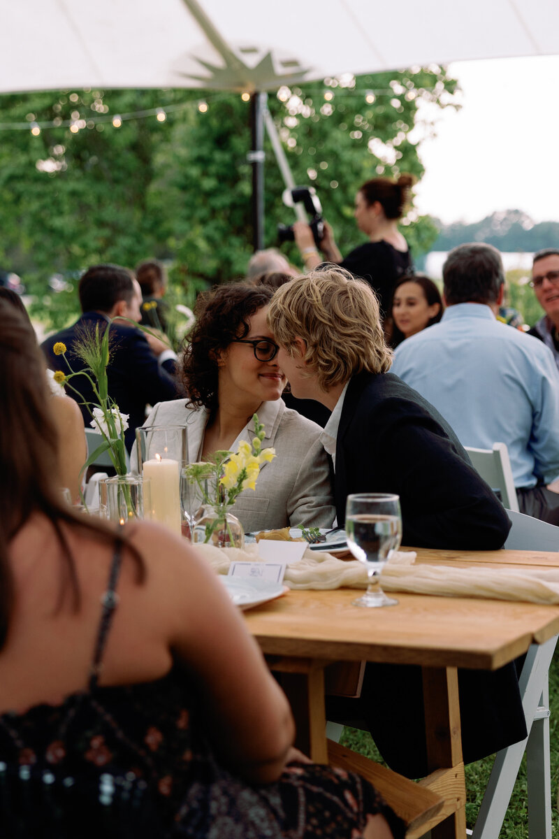 two wedding guests sharing a kiss during a wedding reception