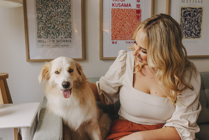 Ashgrove therapist Ashleigh Montgomery sitting on a blue couch with Golden Retriever/Border Collie cross dog named Beanie.