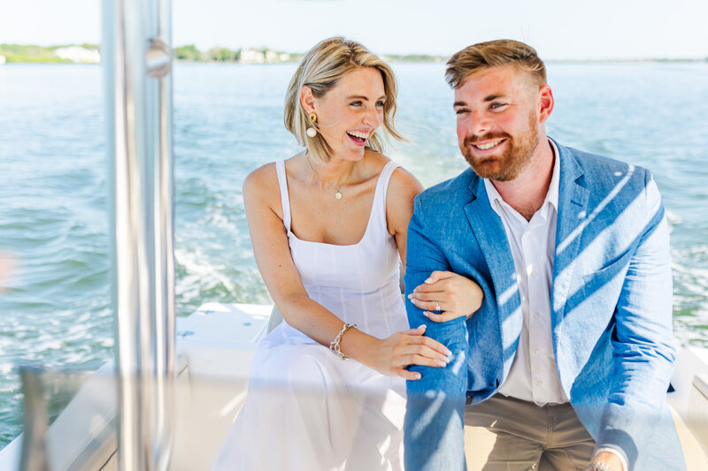 Groom drives boat on the Tampa Bay waters while his bride smiles at him during their engagement photos