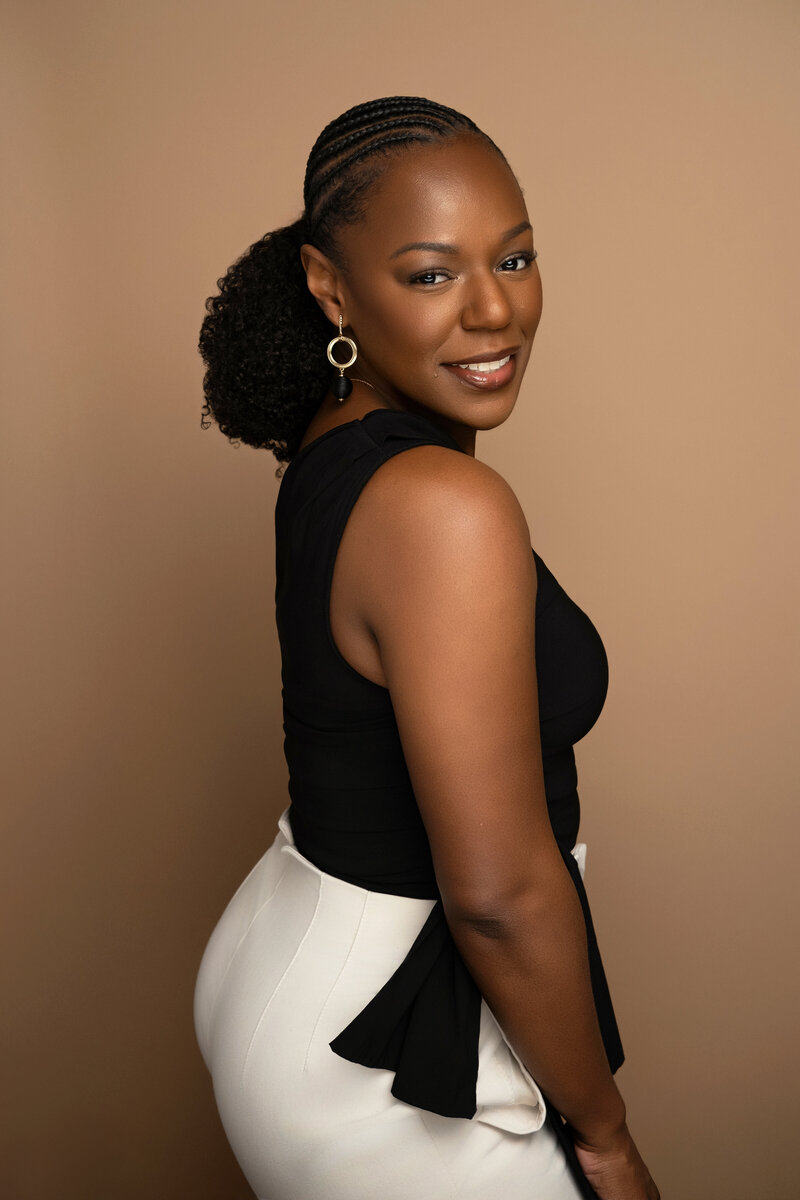 “Rianne Nycole smiling confidently in a black and white outfit against a neutral background—brand strategist and creator of the Clarity Coach GPT and Muse Mode experiences.”