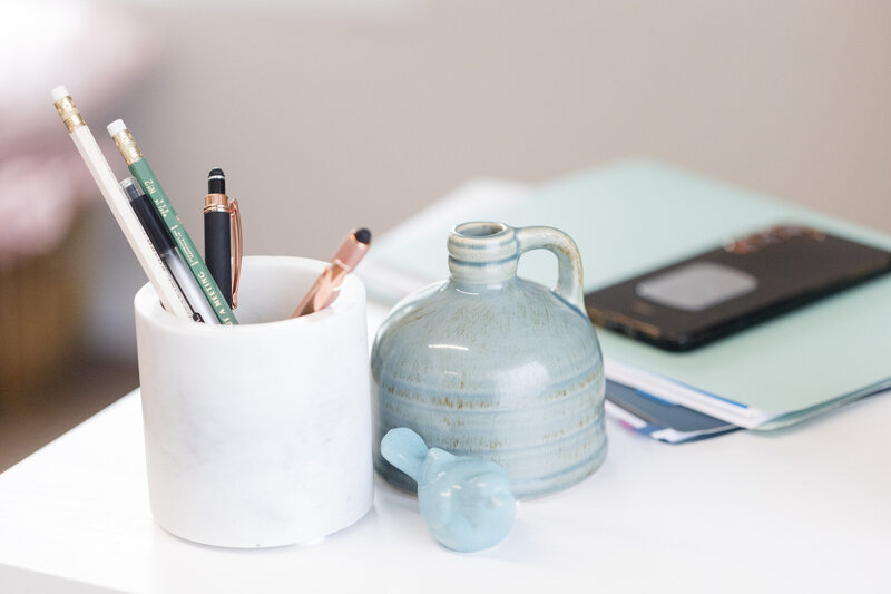 White desk with a marble pencil holder, ceramic jug and blue bird sculpture