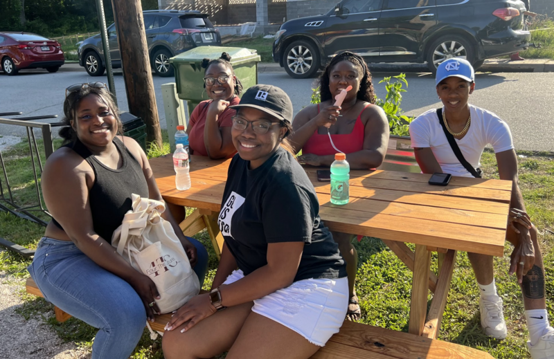 “Local residents gather under tents during an outdoor community event—sharing stories, food, and fellowship as part of ongoing heritage restoration work.”
