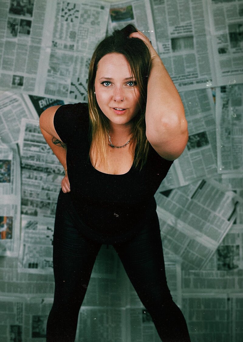 Kristina, life coach for women, standing, leaning forward to the camera with one hand on her hip and one in her hair