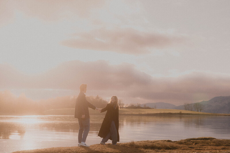 Couple sitting together in front of a large classical portrait inside a historic Scottish art museum, photographed in a cinematic fine art style by wedding photographer Aly Robinson.