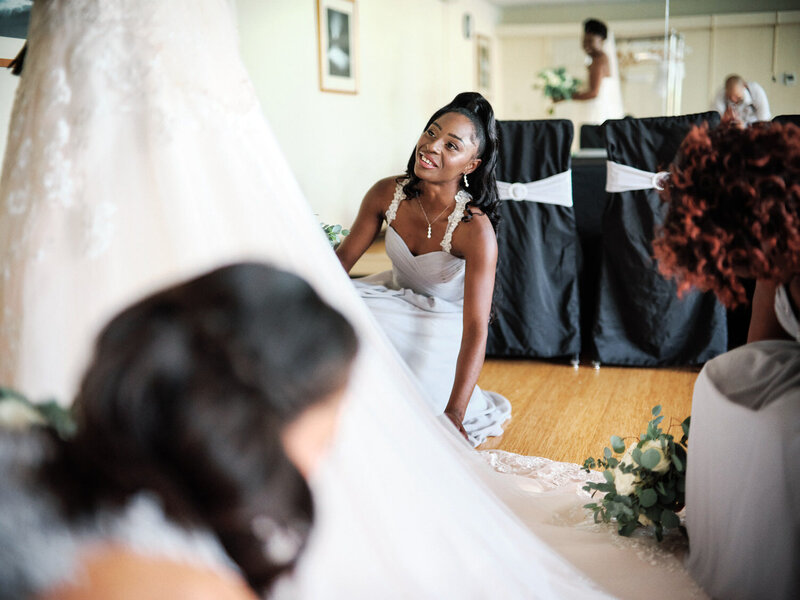 Bridesmaid looks up at the bride as she adjusts her dress
