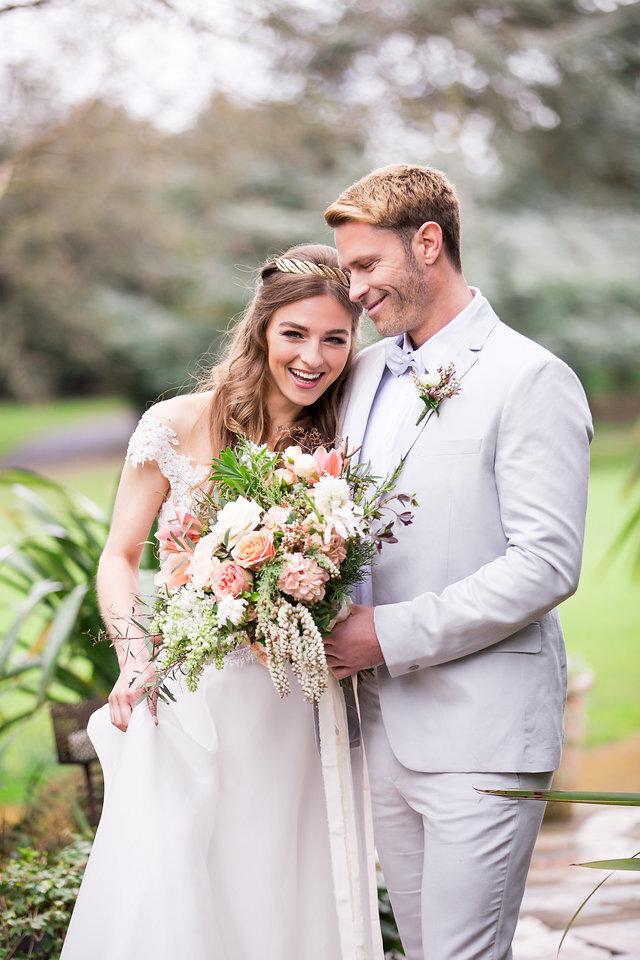 newlywed couple shot from the neck down holding a bouquet of flowers