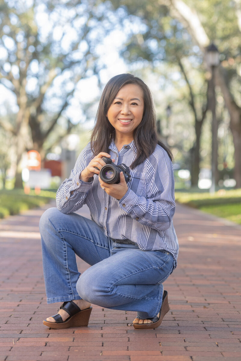 A picture of Khim Higgins, Orlando Senior Photographer holding a camera at Rollins College.