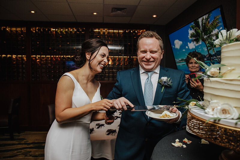 A couple smiling as they cut their cake
