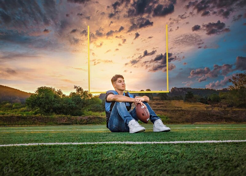 Senior guy posing with his football and helmet on his high school football field. Photo captured by H&N Photography studio