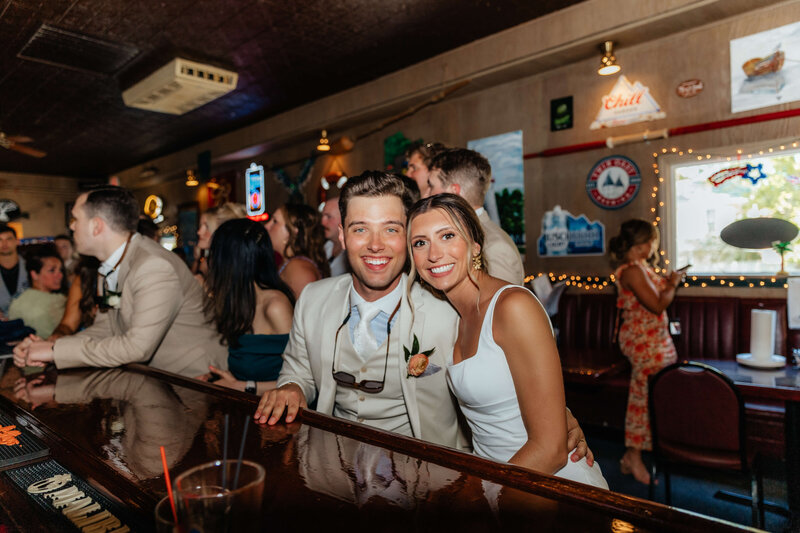 Candid bar photo of newlyweds celebrating with friends, perfect for couples seeking documentary-style Michigan wedding photography.