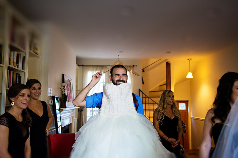 A silly shot of russ hickman holding the brides wedding dress.