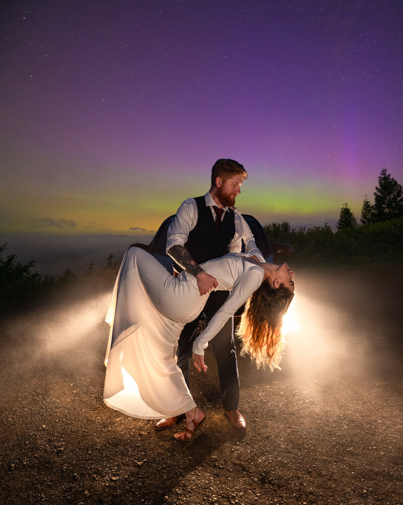 A couple explores the mountains in their wedding attire at night with lanterns