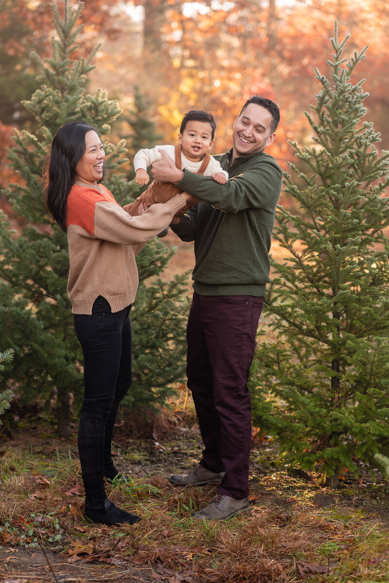 A candid picture of a family smiling at each other with fall leaves in the background
