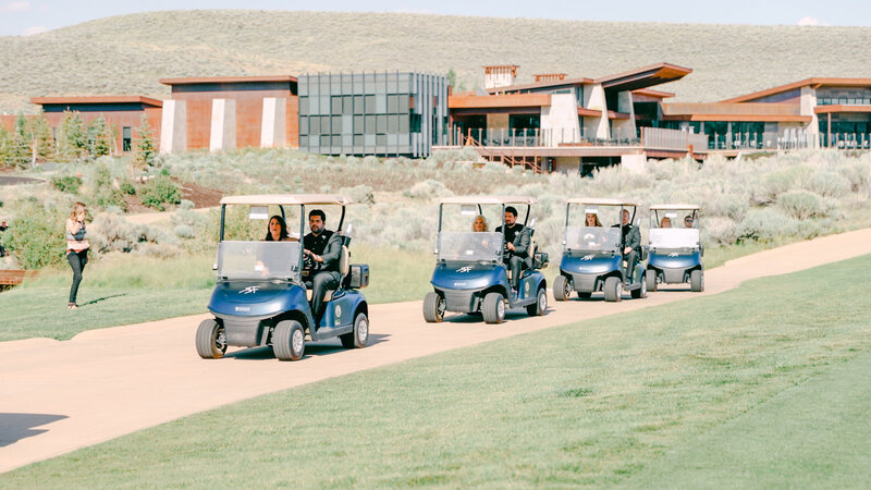 Processional driving to the ceremony in golf carts in front of the promontory club building park city utah, taken by Cali Warner Media