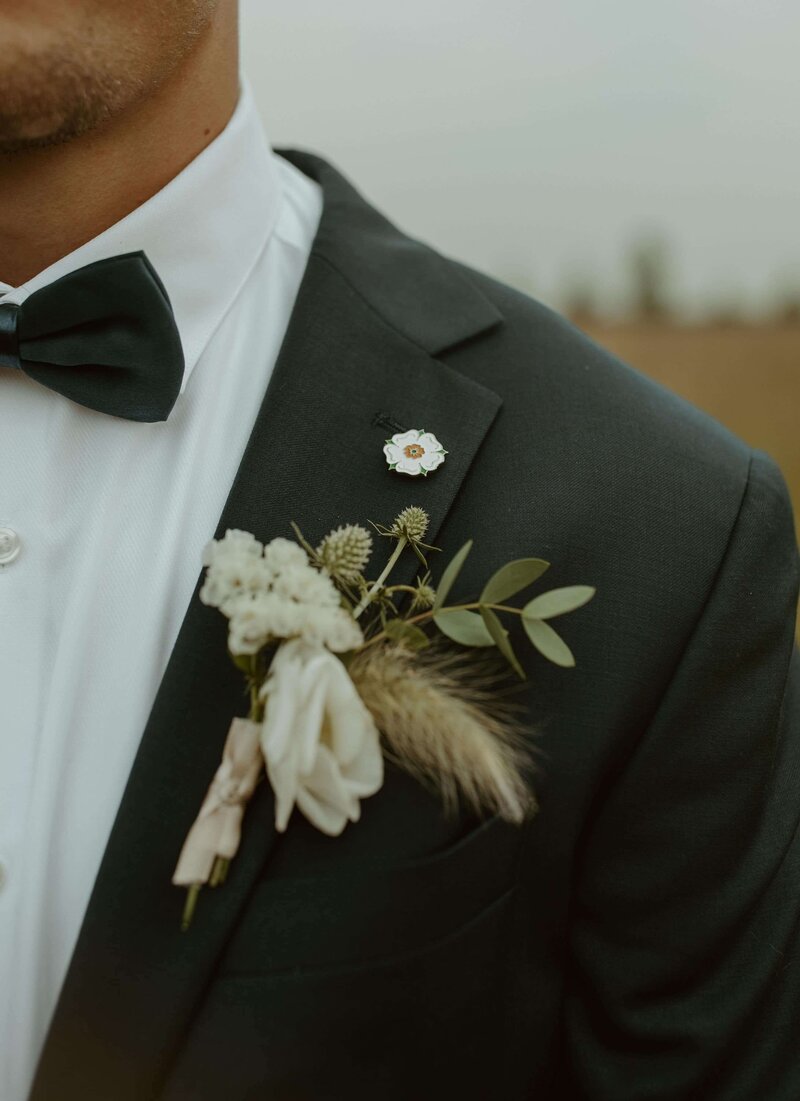 Groom wearing black suit with floral corsage