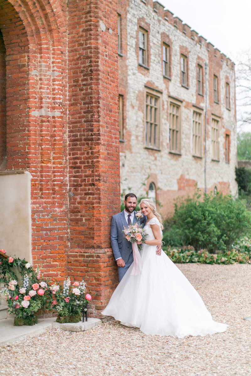 Bride wearing a Suzanne Neville Dress, posing with her Groom at their Farnham Castle wedding