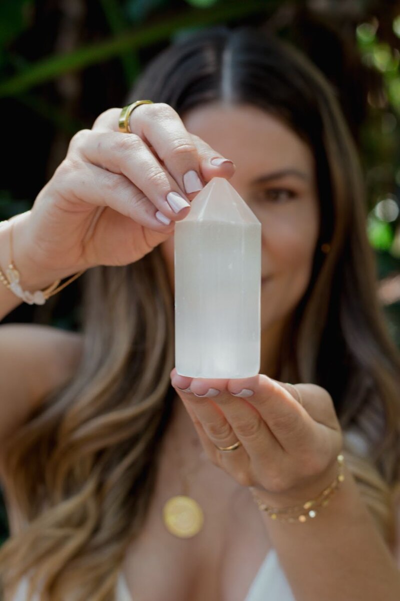 Natalie Bernacchi holding a clear crystal point during a Reiki session, promoting energy healing and chakra balancing.