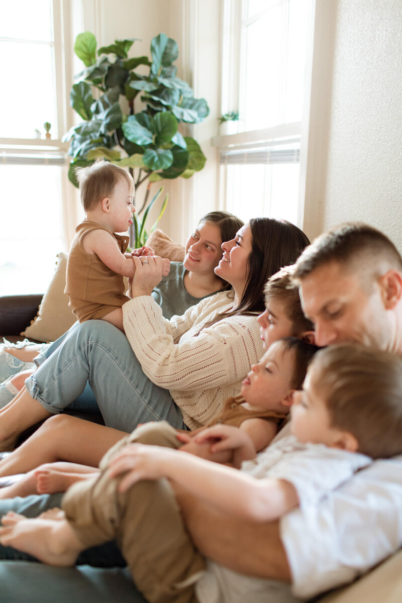 Professional photo of a family of seven snuggling on their couch.