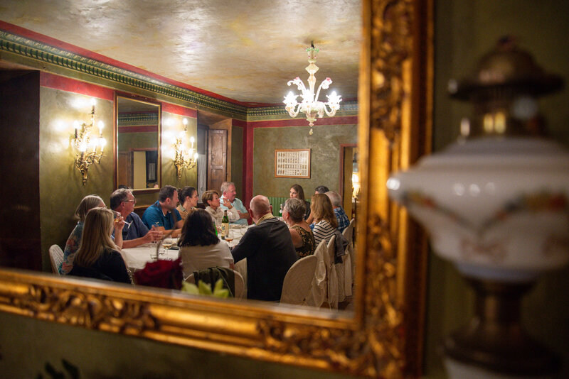 a small group of people enjoying food and wine during their off the beaten path tour of italy