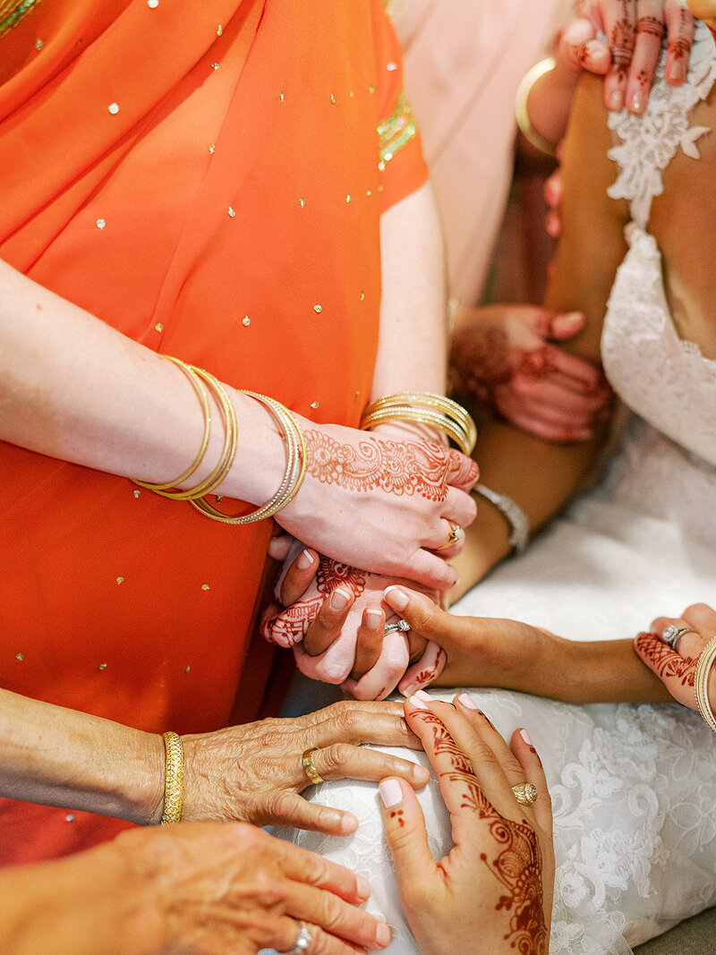 Hands decorated with henna holding the brides' hands