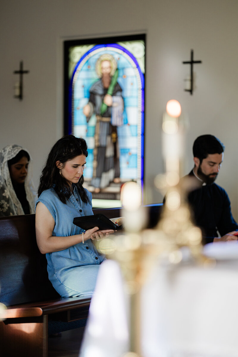 a young woman reading a Bible in a Catholic church