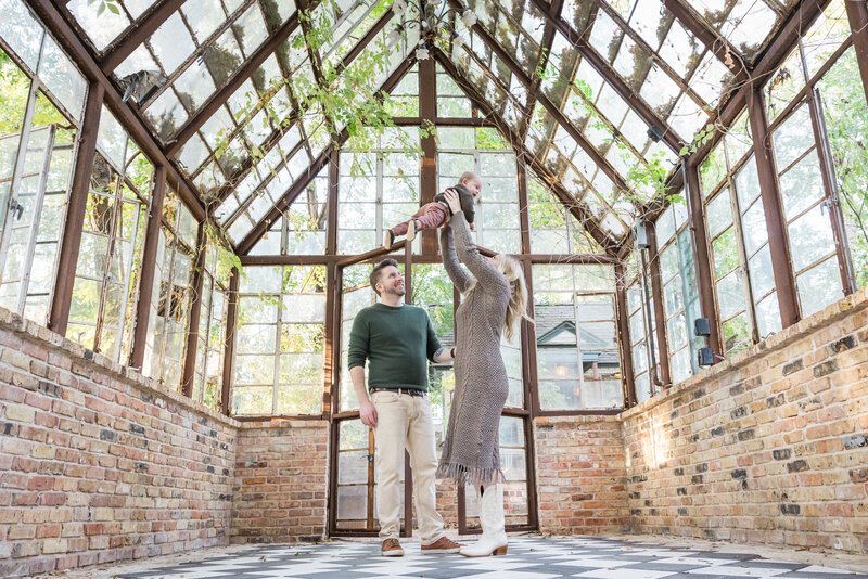 family lifting son in the air in a greenhouse