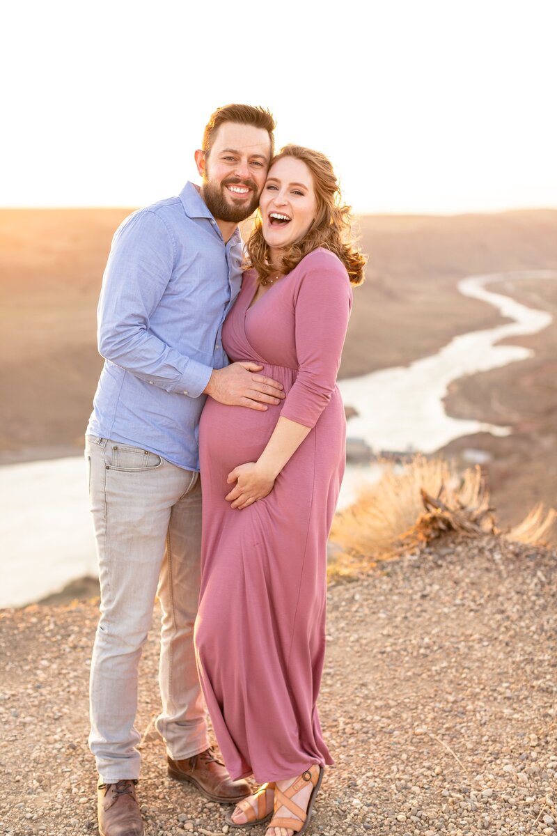 a pregnant woman with her husband standing excitedly in a field