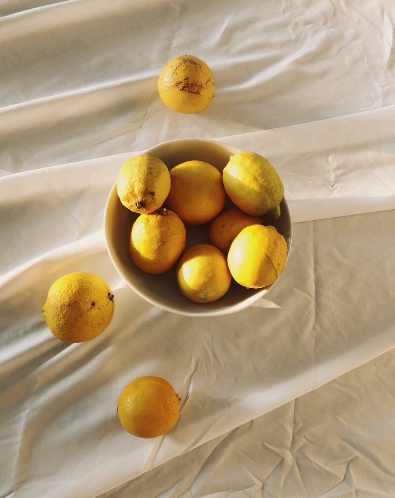 Lemons in a bowl on white fabric