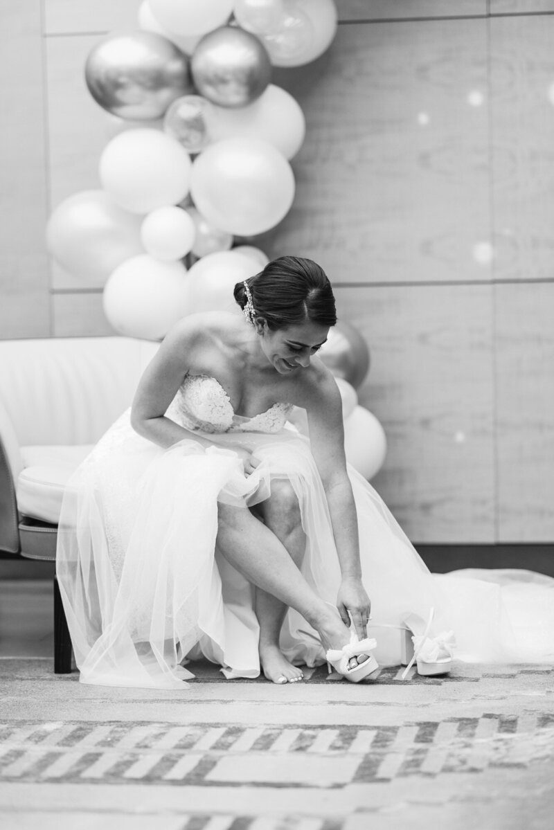 bride putting shoe on in front of balloon arrangement