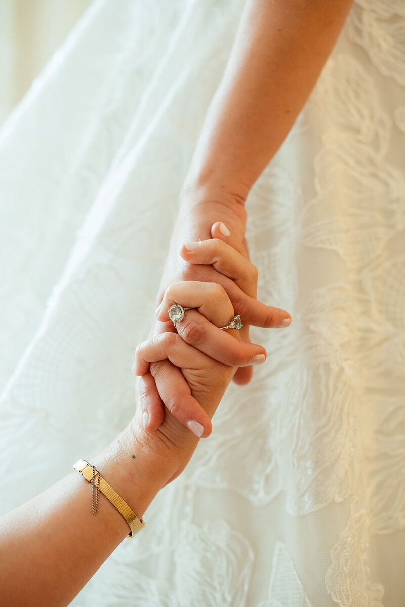 Brides holding hands wtih engagement rings showing