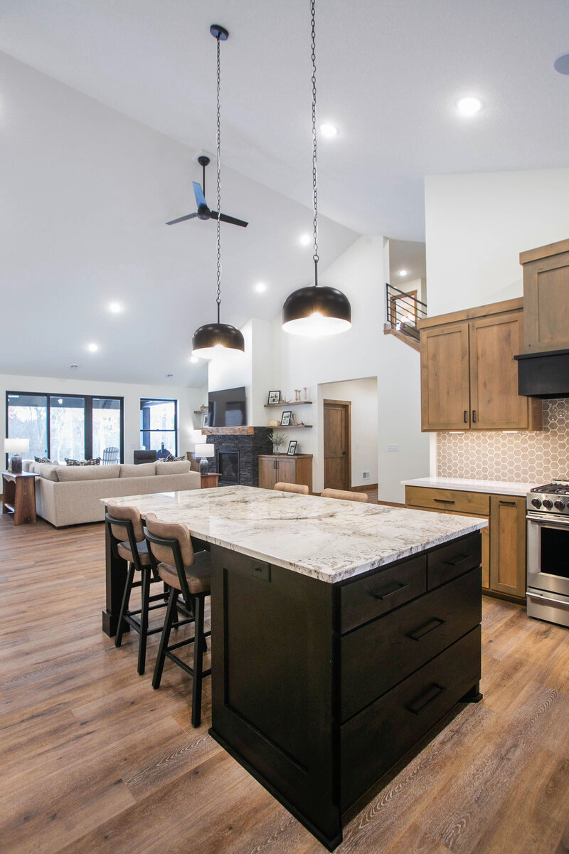Open-concept kitchen in Minnesota custom home with mixed wood cabinetry, large marble island, and modern finishes built by Cornerstone Custom Builds