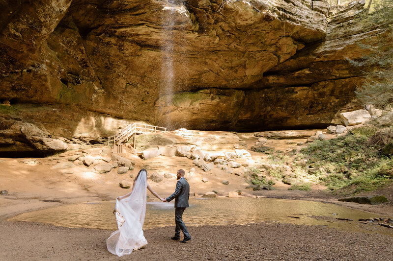 Bride and groom sitting on a bench in the Akron Art Museum with a gallery of paintings behind them. 