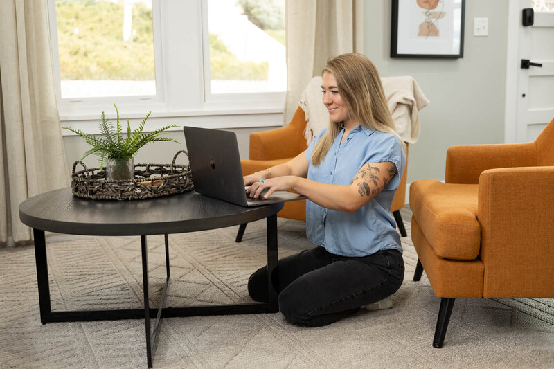 Woman typing on her laptop with a yellow sweater.