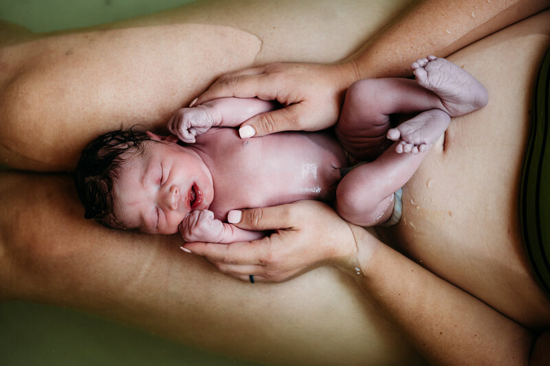 Newborn baby held against mother’s chest immediately after birth — emotional Dallas–Fort Worth birth photography by Poppy + Blue Photography