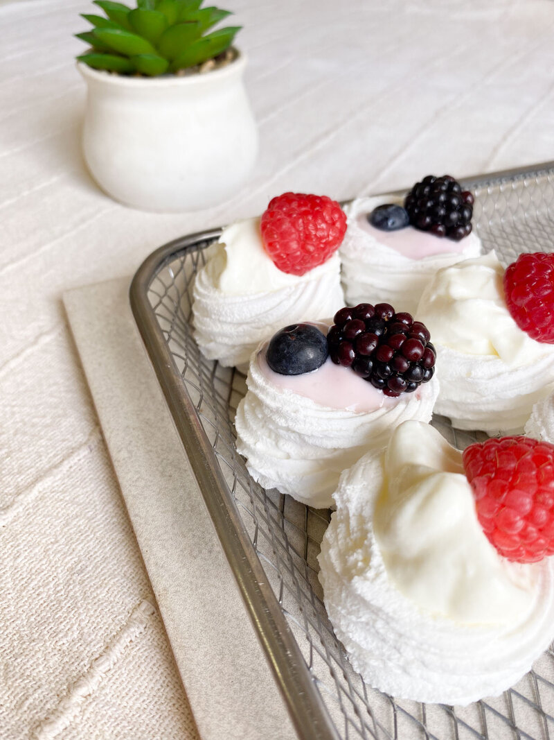 White mini meringue nests with fresh berries.