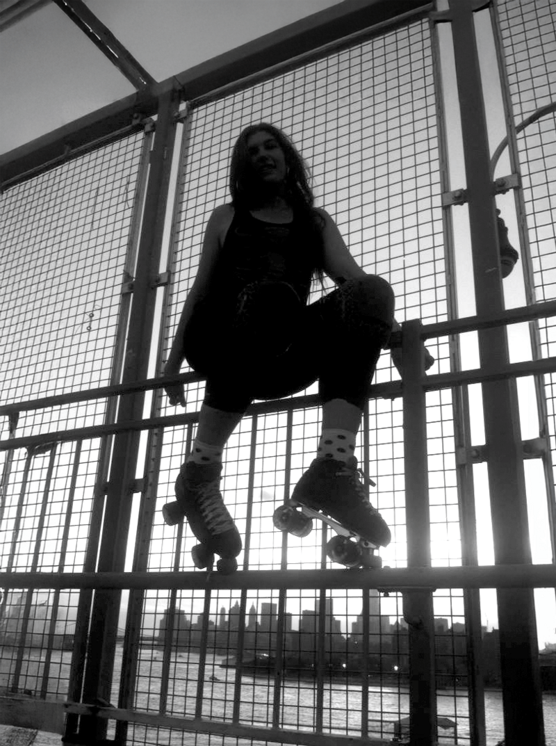 Web Designer Jo Pate in roller skates sitting on Williamsburg bridge fence
