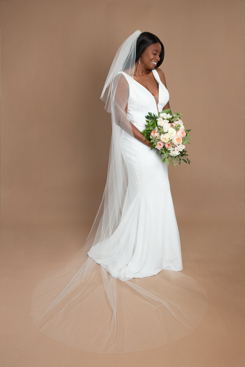 Bride wearing a cathedral length veil with blusher and holding a white and blush bouquet