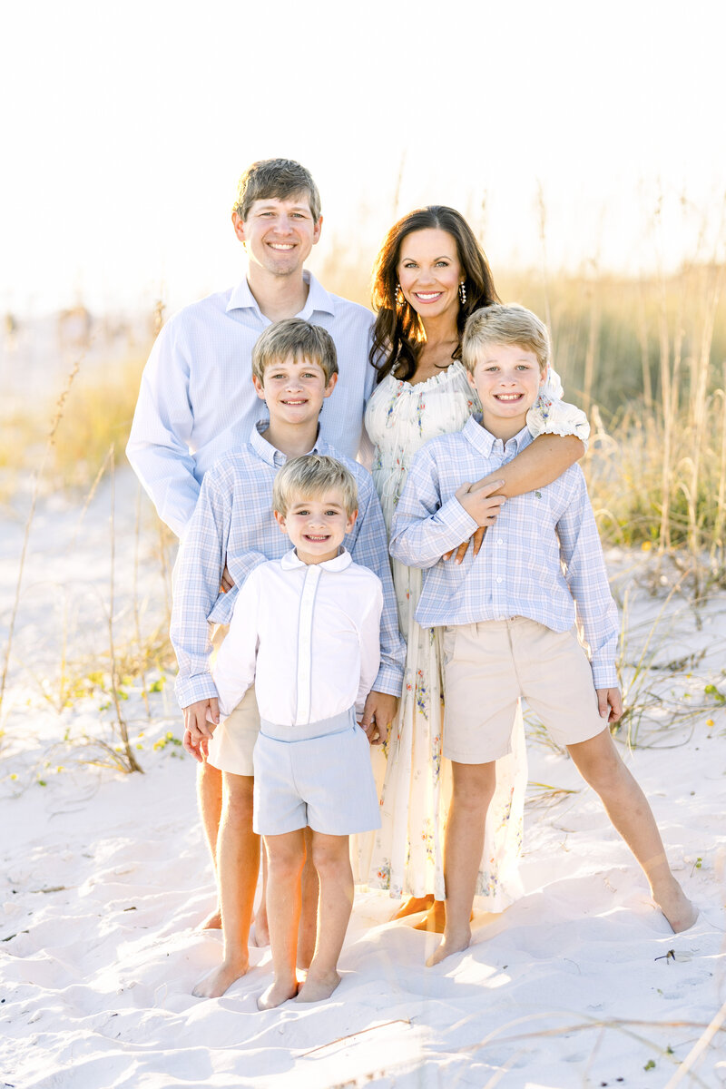Family of 5 posing for a photo on the beach at sunset