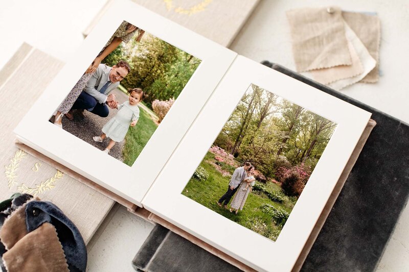 Mockup of a photo album featuring two photos by Delaware family photographer, kristi.  Left side of the album is a photo of dad holding young daughter's hand, and right is mom, dad, and daughter standing together in a field of azaleas at Tyler Arboretum