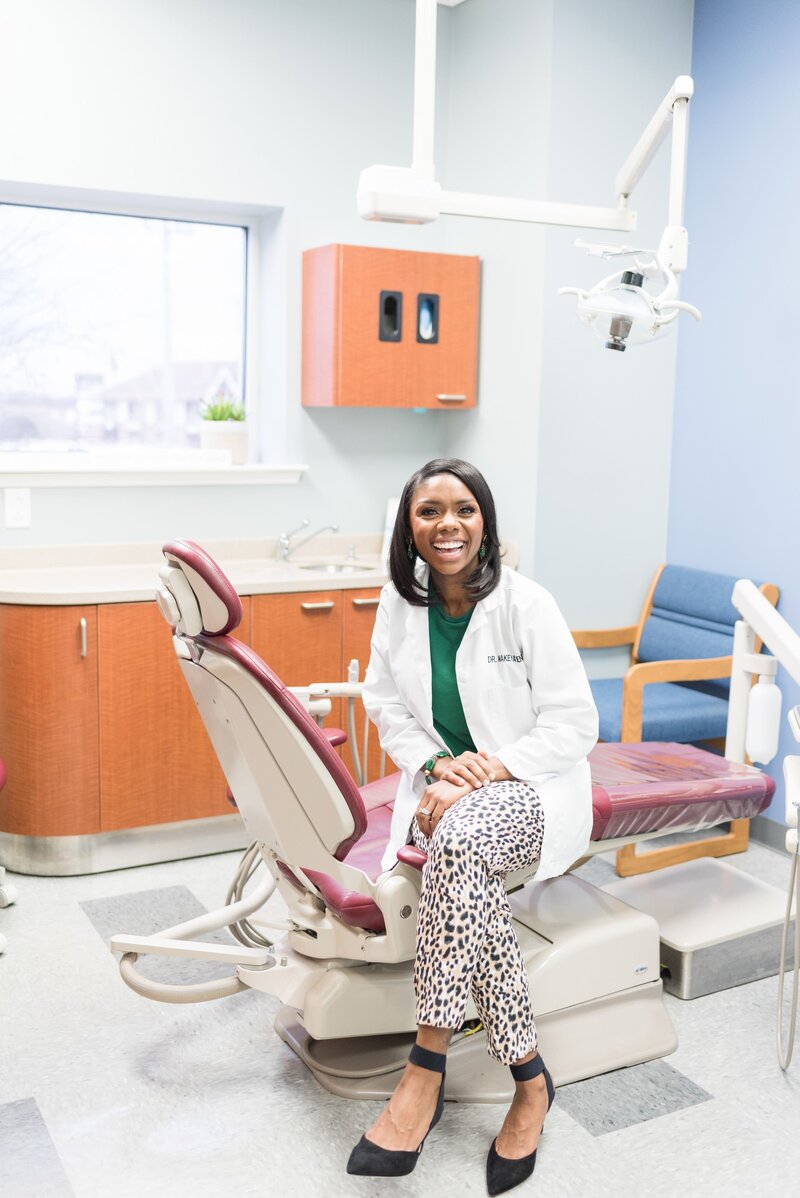 Female dentist sitting on dentist chair in a white lab coat and cheetah print pants