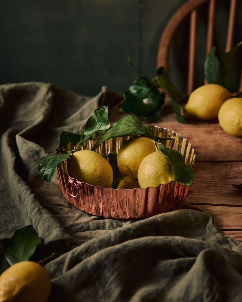 Copper tin with lemons against moody background