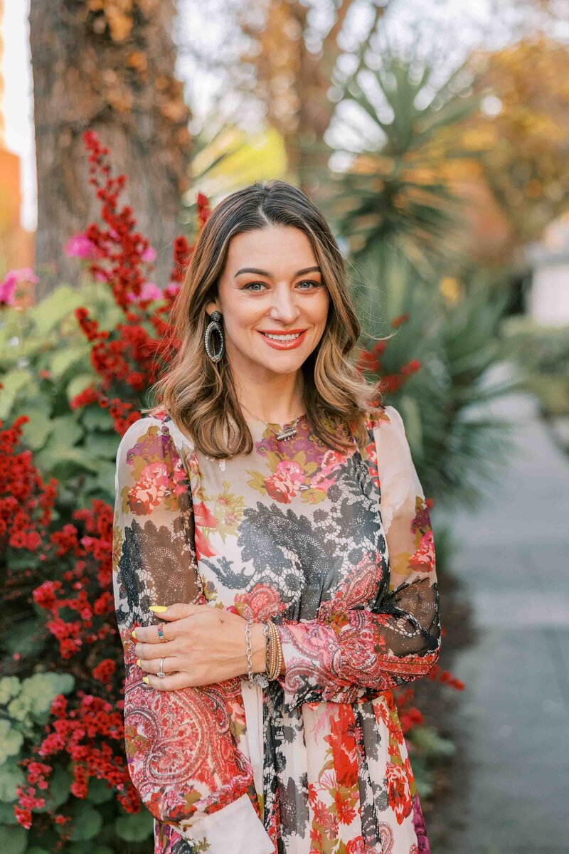 Woman wearing a beautiful floral dress and crossing her arms and smiling at the camera. Bay Area branding headshot for Cassandra McClure